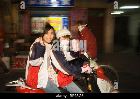 La Chine, Suzhou. Les filles riding scooter. Banque D'Images