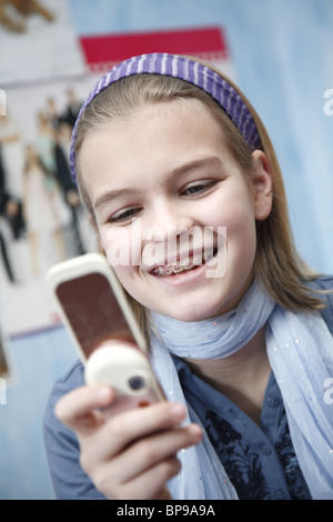 Un 11-year-old girl with braces jouant avec son téléphone portable Banque D'Images