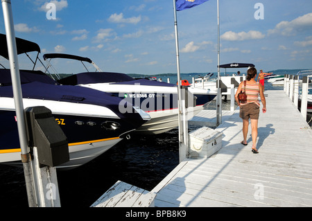 Femme marche sur la jetée du lac bateaux passé sur les ascenseurs. Banque D'Images