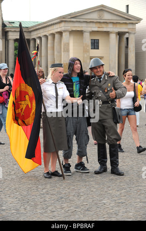 Les jeunes paient pour avoir pris en photo l'homme en uniforme de la RDA La Porte de Brandebourg Berlin Allemagne Deutschland Europe Banque D'Images