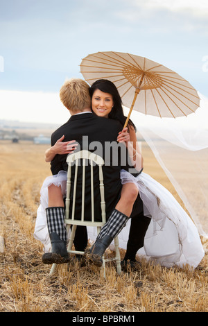 Three Hills, Alberta, Canada ; une femme et un homme assis sur une chaise dans un champ agricole Banque D'Images