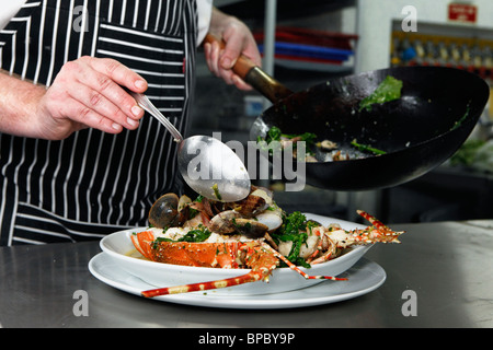 Un chef cuisinier prépare un plat de fruits de mer Banque D'Images