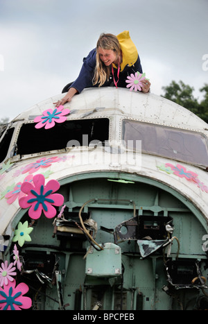 Un artiste décore un vieil avion RAF avec fleurs dans la région de la ville de Corbeille au festival de Glastonbury Pilton site UK Banque D'Images