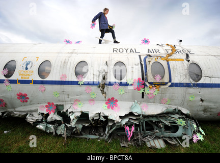 Un artiste décore un vieil avion RAF avec fleurs dans la région de la ville de Corbeille au festival de Glastonbury Pilton site UK Banque D'Images