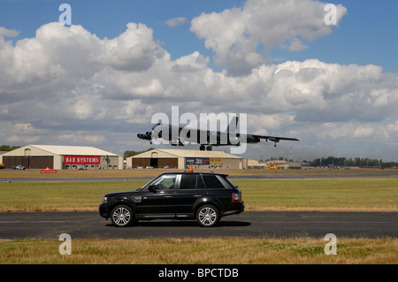 La Range Rover 4x4 automobile attend de traverser la piste en direct alors qu'un américain B52 bombardier lourd atterrit à l 2010 RIAT Banque D'Images