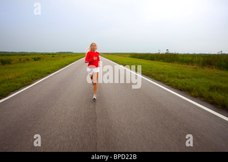 Young woman jogging on country road Banque D'Images