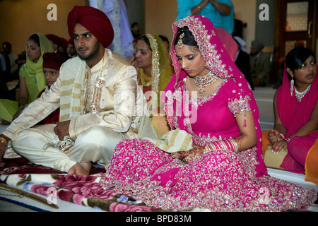 Une cérémonie de mariage sikh en Angleterre. Mariée est maintenant la palla le collage à son nouveau mari. Banque D'Images