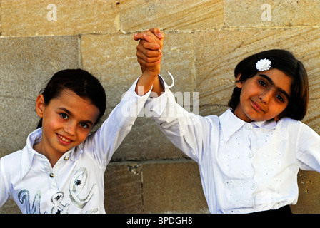 L'Azerbaïdjan, Bakou, deux jeunes girls holding hands against wall Banque D'Images