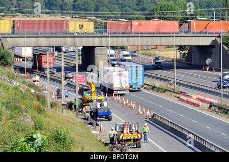 Transport par train de fret chargé de conteneurs d'expédition sur le pont au-dessus des camions la route travaille sur l'autoroute M 25 à la sortie 28 Brentwood Essex Angleterre Banque D'Images