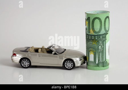 Un modèle de voiture et un rouleau de billets en euros Banque D'Images