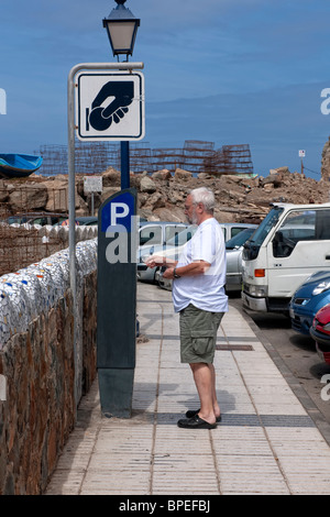 L'homme mettant l'argent dans un parking Gare paye (parking meter) à Puerto de Mogan, Grande Canarie Banque D'Images