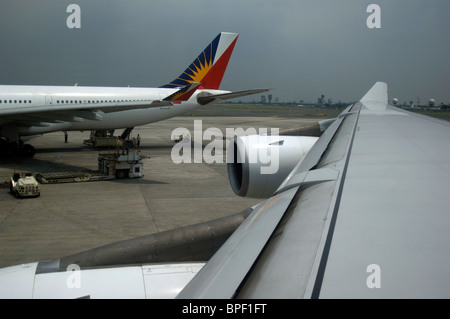 Philippine Airlines avions stationné jusqu'à l'aéroport International de Ninoy Aquino, Manille, Philippines comme une tempête entre en jeu. Banque D'Images