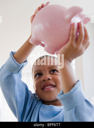 African American boy lifting piggy bank Banque D'Images