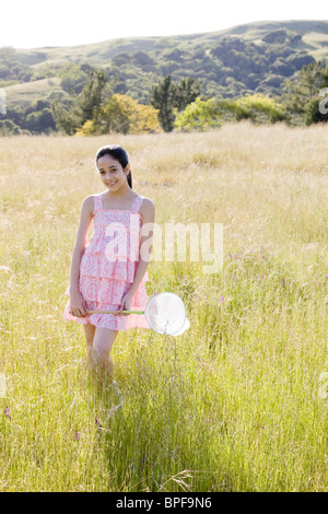 Young girl in field holding net Banque D'Images