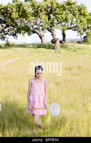 Young girl in field holding net Banque D'Images