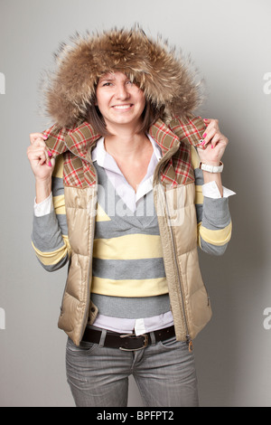 Femme souriante en tenue d'hiver avec capuche doublée de fourrure Banque D'Images