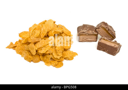 Tas de flocons de maïs avec des tranches de barre de chocolat à partir de la perspective peu isolés contre blanc. Banque D'Images