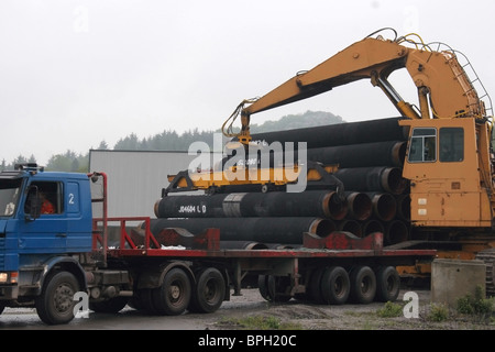 Grue jaune chargement de gros diamètre dans le semi-remorque sur l'aire d'entreposage. Banque D'Images