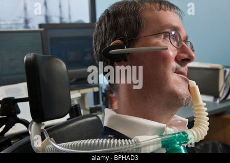 Businessman with duchenne muscular dystrophy dans un fauteuil roulant motorisé à l'aide d'un ventilateur et d'une respiration dans un appareil auditif Banque D'Images