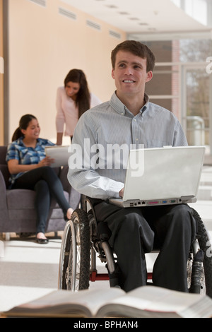 Avec l'enseignant de la moelle épinière en fauteuil roulant avec leurs élèves dans l'arrière-plan Banque D'Images