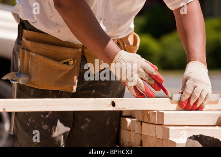 Carpenter measuring goujons de mur sur un site de construction Banque D'Images