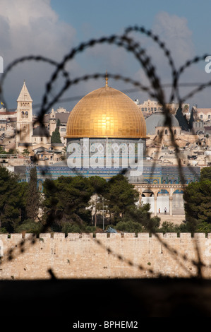 La vieille ville de Jérusalem, y compris le Dôme du Rocher et différents clochers, vu à travers des rouleaux de barbelés. Banque D'Images