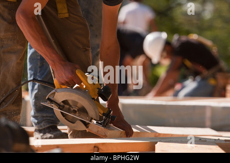 Les charpentiers en utilisant une scie circulaire sur un site de construction Banque D'Images