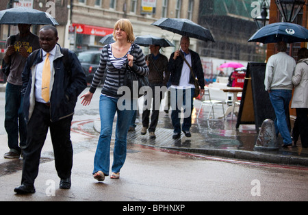 Les personnes qui traversent la rue sur après-midi pluvieux dans le sud de Londres, SE1, Angleterre, Royaume-Uni. Banque D'Images