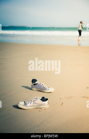 Chaussures à gauche sur une plage de sable. Propriétaire peut être vu dans la distance se déversant dans la mer Banque D'Images