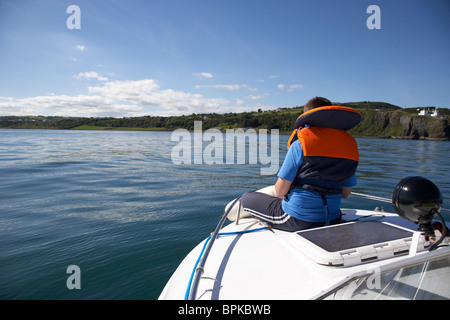 10 year old boy wearing gilet tranquillement assis à l'avant d'un bateau en mer Banque D'Images