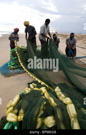 Les pêcheurs sont la préparation de filets pour le lendemain sur la plage près du village de pêcheurs en mer de Gopalpur, Orissa, Inde. Banque D'Images