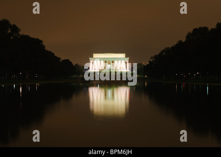 Lincoln Memorial Reflecting Pool la nuit Washington DC // WASHINGTON DC — le Lincoln Memorial brille sur le ciel nocturne, ses colonnes illuminées se reflétant dans la surface miroir de la piscine réfléchissante. L'image du mémorial double sur l'eau calme, créant une scène symétrique. Le bassin réfléchissant de 2 029 pieds de long s'étend vers l'est en direction du Washington Monument. Banque D'Images