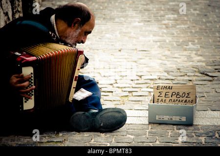 Ancien immigrant serbe jouant pour l'argent dans les rues d'Athènes, Grèce. Banque D'Images