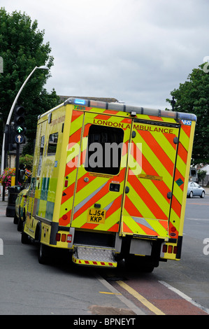 London Ambulance garé à moitié sur trottoir avec les clignotants, tout en assistant à une urgence Banque D'Images