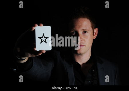 Jeune homme blanc magicien avec ginger hair posant avec star carte à jouer en studio Banque D'Images