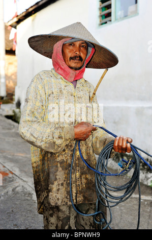 Homme marchant dans la rue du village avec son équipe de buffles d'eau java indonésie Banque D'Images