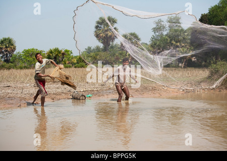 Jeune homme à l'aide d'un jet filet pour attraper des poissons dans le Cambodge rural Banque D'Images