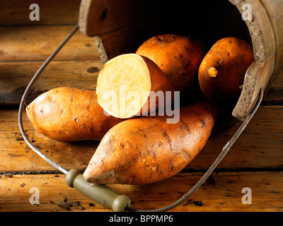 Bug Frais de patates douces dans un seau en bois rustique sur une table en bois Banque D'Images