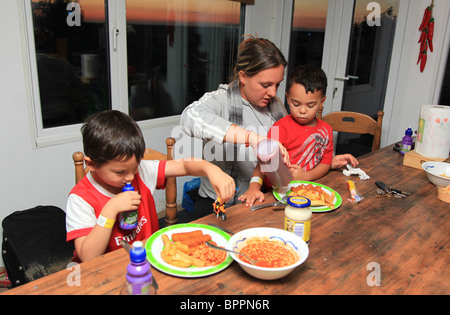 Les jeunes garçons ayant leur dîner avec maman. Banque D'Images