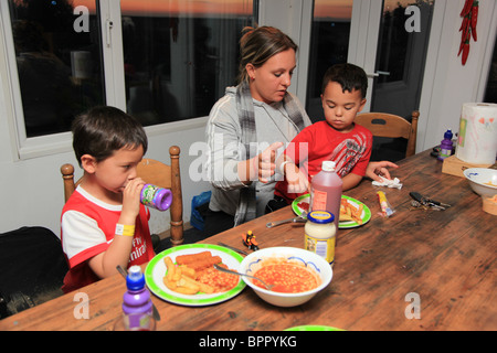 Les jeunes garçons ayant leur dîner avec maman. Banque D'Images