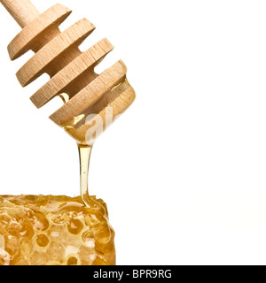 Dégoulinant de miel naturel drizzler en bois isolé sur blanc. Banque D'Images