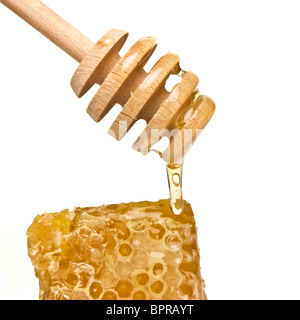 Dégoulinant de miel naturel drizzler en bois isolé sur blanc. Banque D'Images
