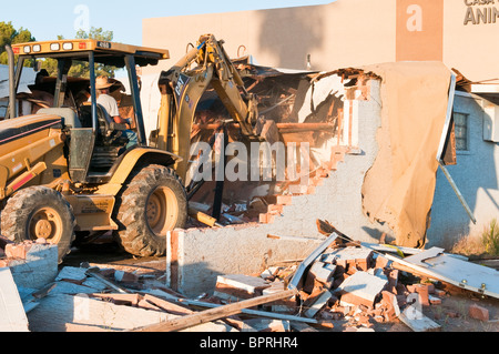 Une pelleteuse est utilisée pour abattre un vieil immeuble commercial et faire place à un nouveau. Banque D'Images