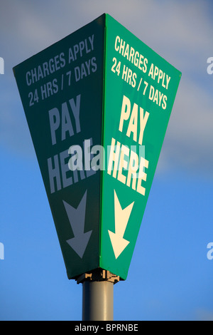 Poteau de signalisation dans un parking indiquant où payer et que des frais s'appliquent en tout temps. Banque D'Images