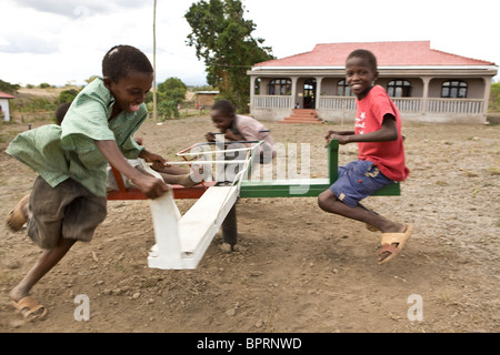 Les enfants jouent sur l'Afrique d'un manège dans un orphelinat à Kilimandjaro, Tanzanie. Banque D'Images