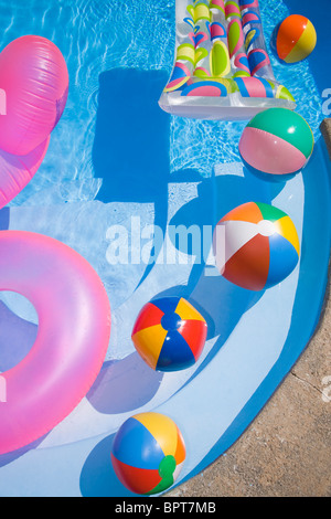 Des ballons de plage et des jouets dans une piscine bleu pétillant Banque D'Images