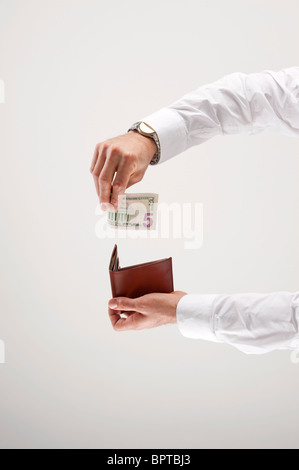Homme met cinq dollars dans Wallet Banque D'Images