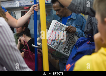 Homme de journal Sun lisant sur London Underground UK. 4 septembre 2010 The Sun Newspaper est un tabloïd britannique 'Red Top' et fait partie des Newspapers de Rupert Murdoch's News Group, News UK, News Corp Newscorp business. HOMER SYKES Banque D'Images