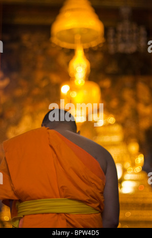 Un moine s'agenouille devant une statue de Bouddha de Wat Po, Grand Palace, Bangkok, Thaïlande. L'Indochine. En Asie du sud-est. Janvier 2010 Banque D'Images