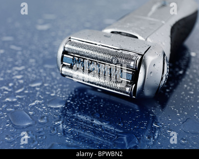 Fleuret électrique haut de gamme rasoir humide sur fond de verre bleu avec des gouttes d'eau sur elle Banque D'Images